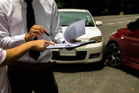 people with paperwork in front of car accident